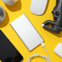 Power banks and headphones on yellow background, top view